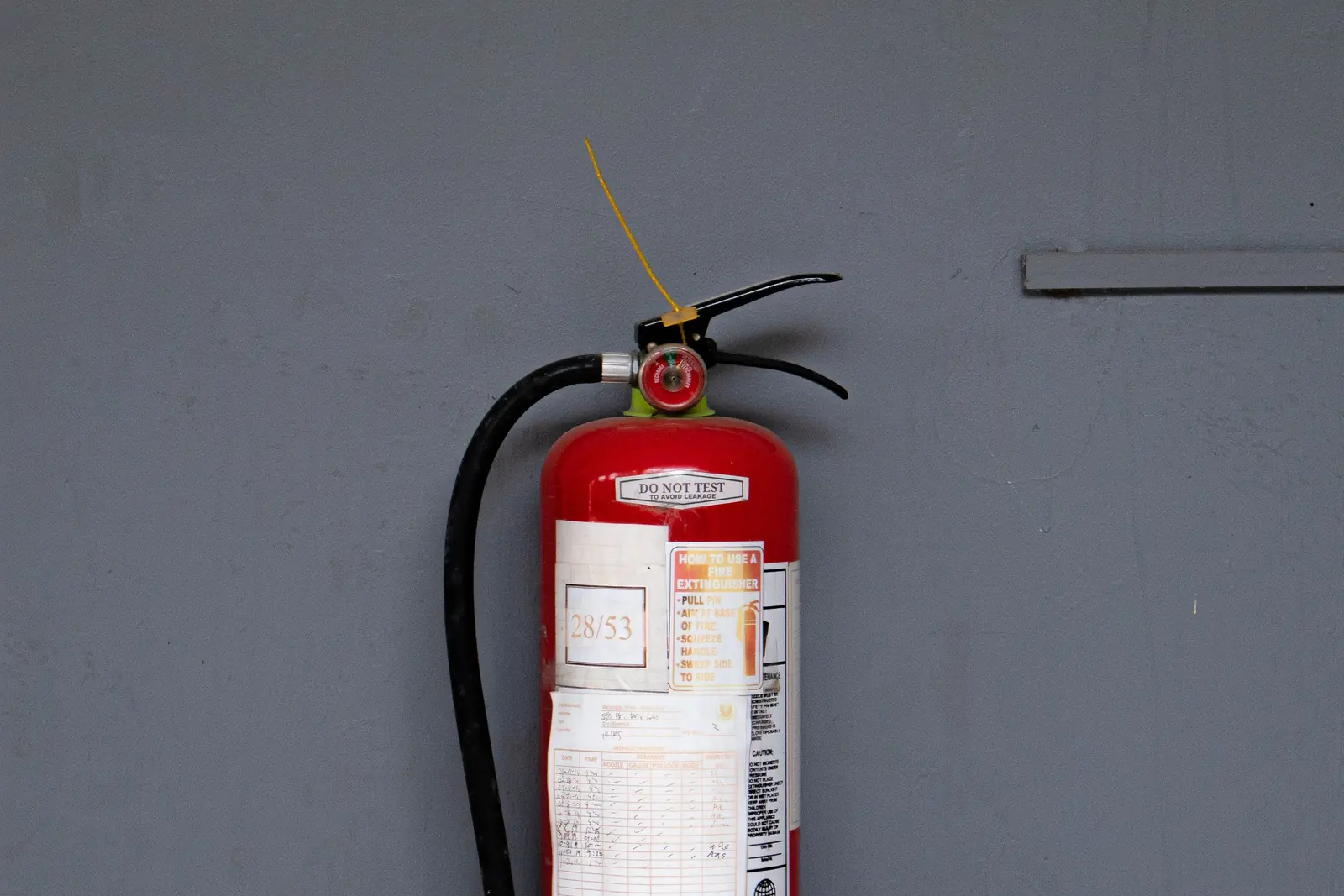Red fire extinguisher standing against a gray wall