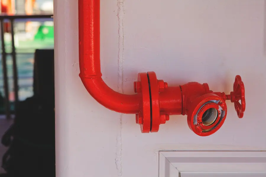 Red fire protection valve mounted on a white wall