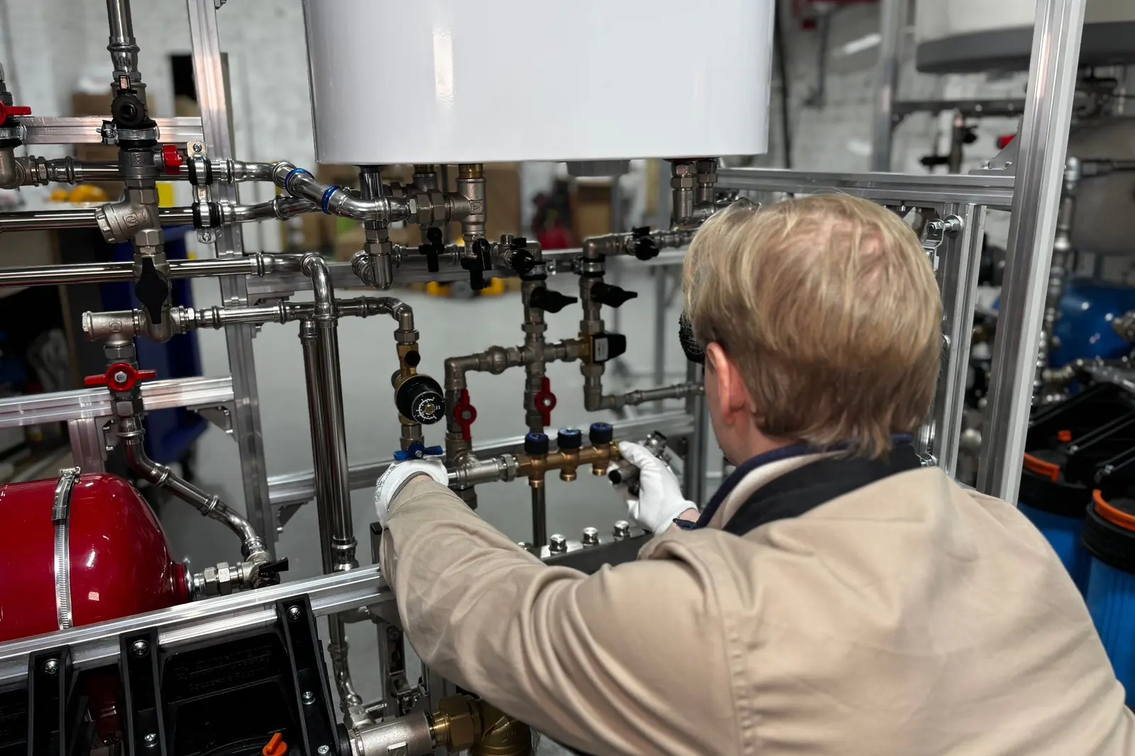 Technician adjusting valves on a piping system in a building mechanical room