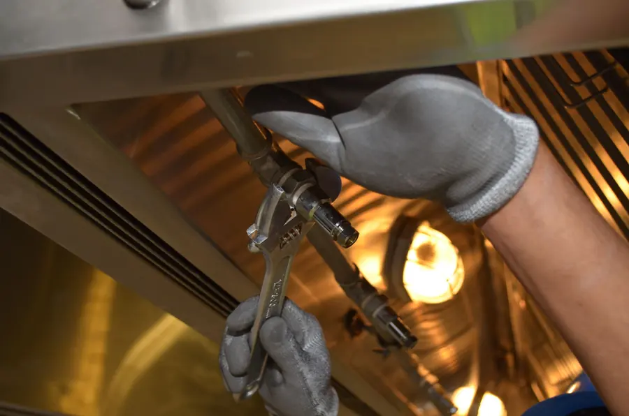 Service worker tightening a pipe fitting with a wrench