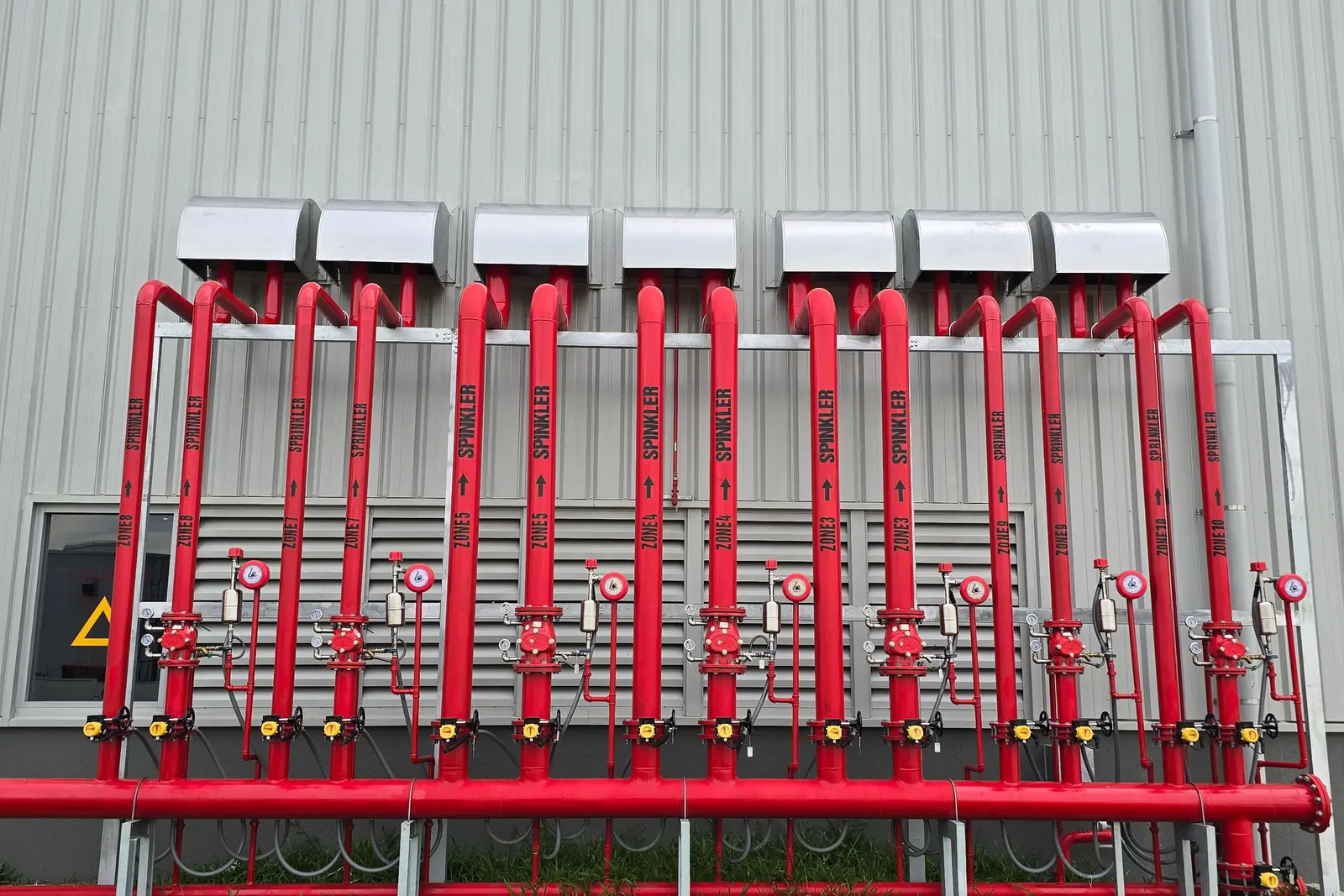 Red fire sprinkler system pipes running along a building wall